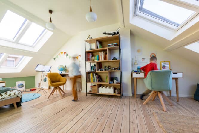 Chambre d'enfants mansardée avec plafond en pente et fenêtres de toit VELUX, décoration colorée.