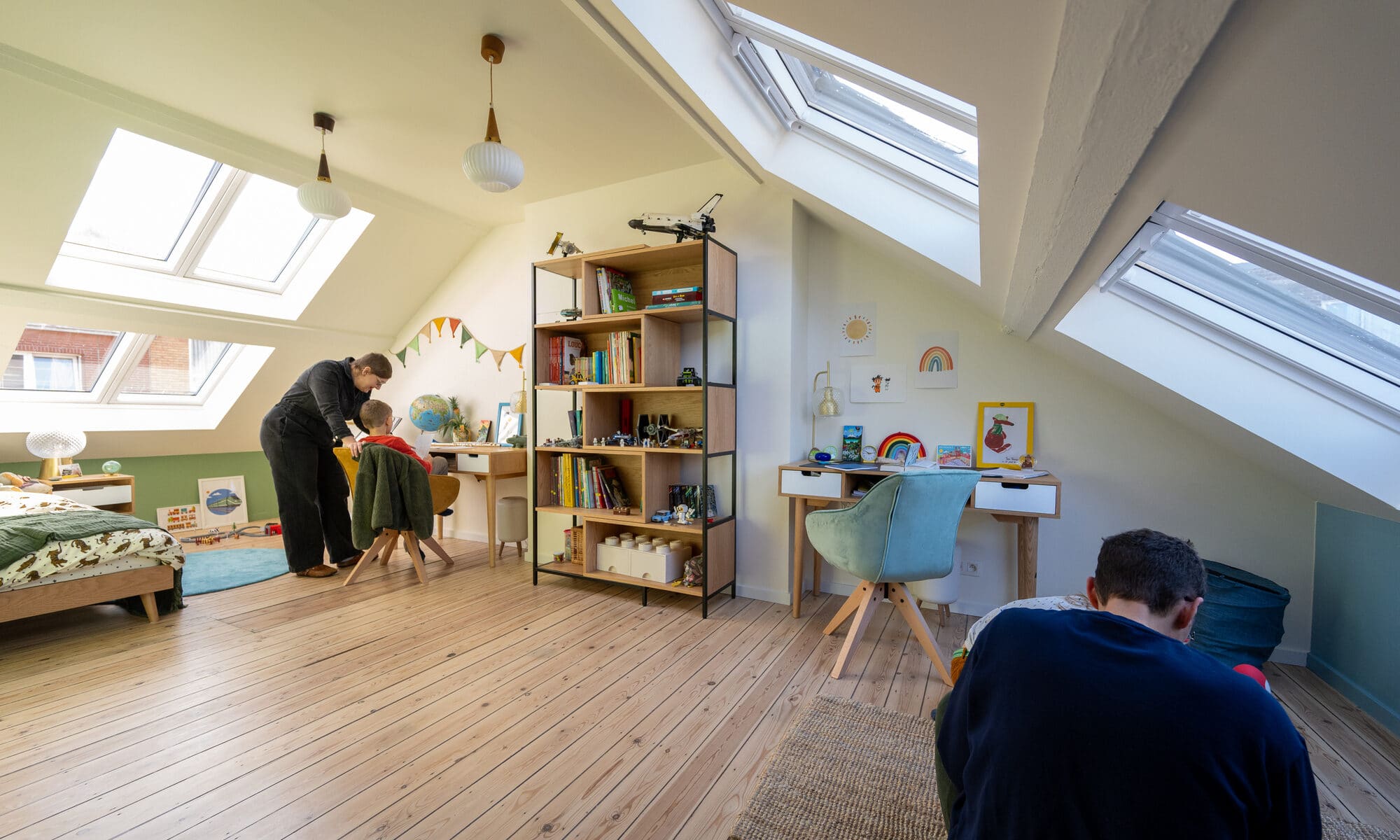 Chambre d'enfants mansardée avec plafond en pente et fenêtres de toit VELUX, lumineuse et ludique.