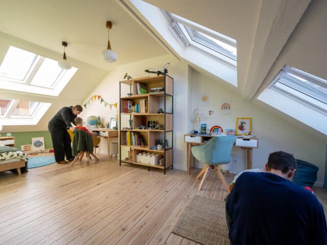 Chambre d'enfants mansardée avec plafond en pente et fenêtres de toit VELUX, lumineuse et ludique.