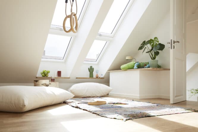 Chambre mansardée avec plafond en pente et fenêtres de toit VELUX, décor lumineux et chaleureux.