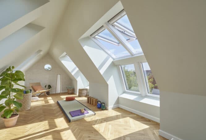 Salle de yoga mansardée avec plafond en pente et fenêtres de toit VELUX, lumière naturelle.