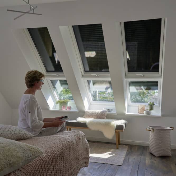 Chambre mansardée avec plafond en pente et fenêtres de toit VELUX, baignée de lumière naturelle.