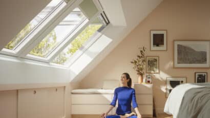 Chambre mansardée avec plafond en pente, fenêtre de toit VELUX ouverte, tapis de yoga.