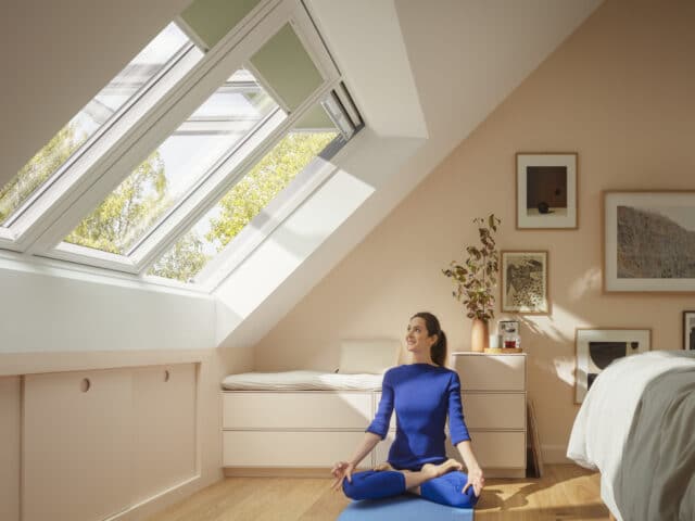 Chambre mansardée avec plafond en pente, fenêtre de toit VELUX ouverte, tapis de yoga.