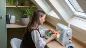 Atelier de couture mansardé avec plafond incliné et fenêtre de toit VELUX, machine à coudre sur le bureau.