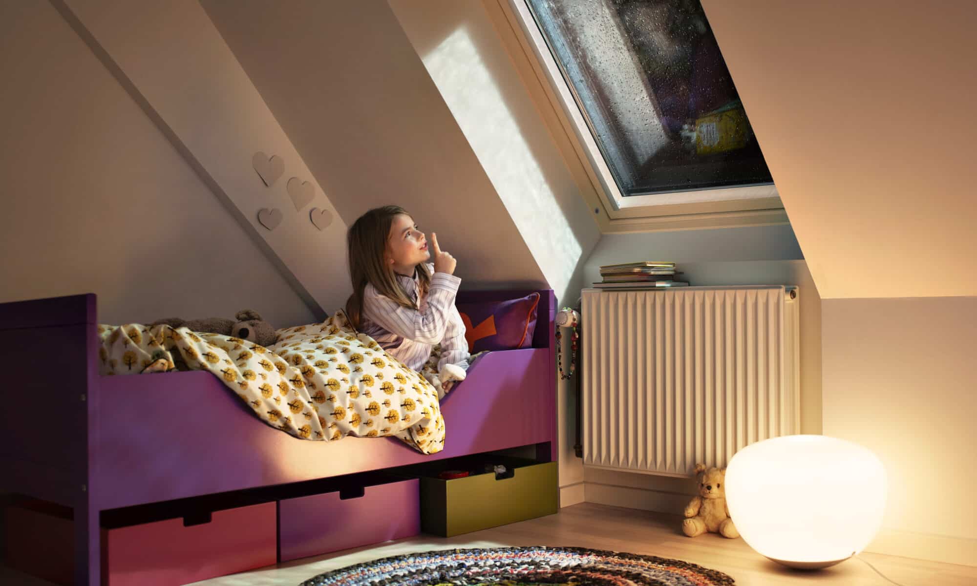 Chambre d'enfant mansardée avec plafond incliné et fenêtre de toit VELUX, décoration chaleureuse.