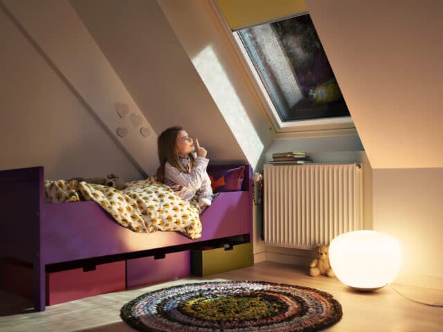 Chambre d'enfant mansardée avec plafond incliné et fenêtre de toit VELUX, décoration chaleureuse.