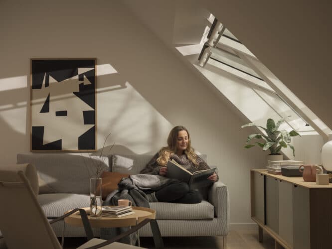 Salon mansardé avec plafond incliné et fenêtre de toit VELUX, décoration chaleureuse.