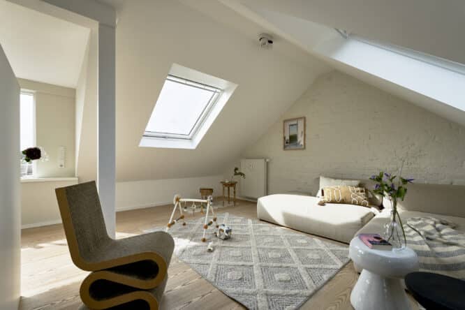 Chambre mansardée avec plafond en pente, fenêtre de toit VELUX, décoration chaleureuse.