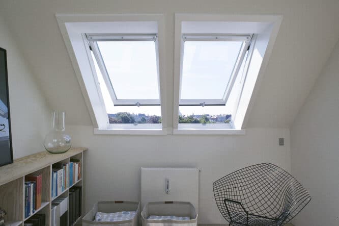 Chambre mansardée avec fenêtres de toit VELUX, plafond en pente et décoration minimaliste.