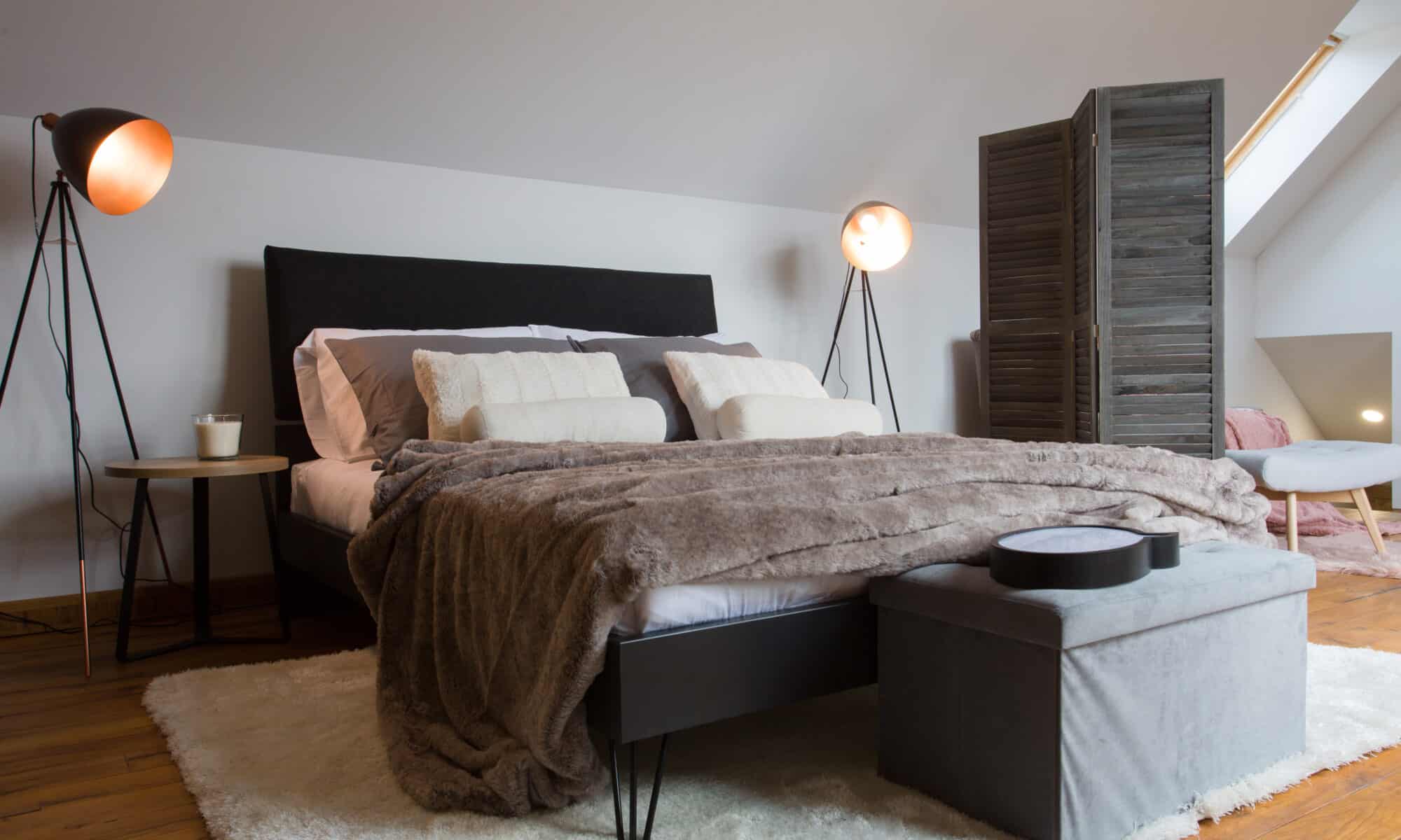 Chambre mansardée avec plafond incliné et fenêtre de toit VELUX, confortable et accueillante.