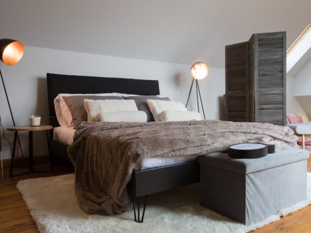 Chambre mansardée avec plafond incliné et fenêtre de toit VELUX, confortable et accueillante.