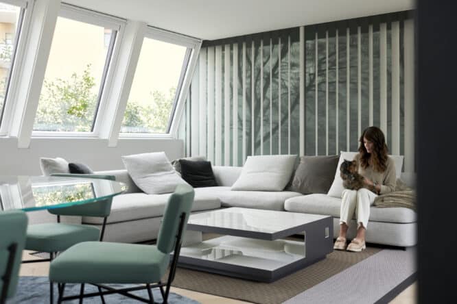 Salon avec grandes fenêtres, canapé d'angle et table basse.