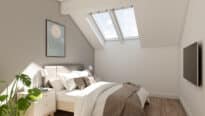 Chambre mansardée avec plafond incliné et fenêtres de toit VELUX, laissant entrer la lumière naturelle.