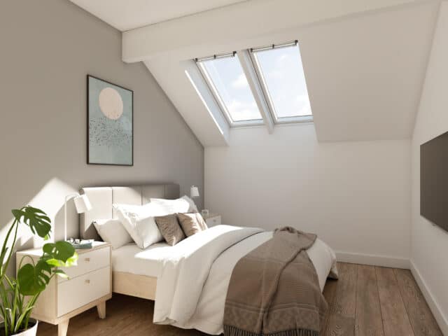 Chambre mansardée avec plafond incliné et fenêtres de toit VELUX, laissant entrer la lumière naturelle.