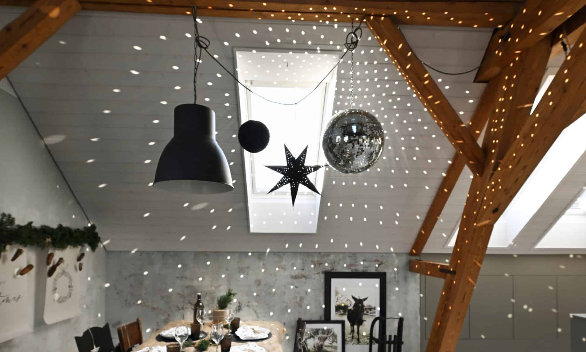 Salle à manger mansardée avec plafond en pente, poutres apparentes et décorations festives.
