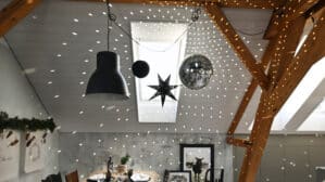 Salle à manger mansardée avec plafond en pente, poutres apparentes et décorations festives.