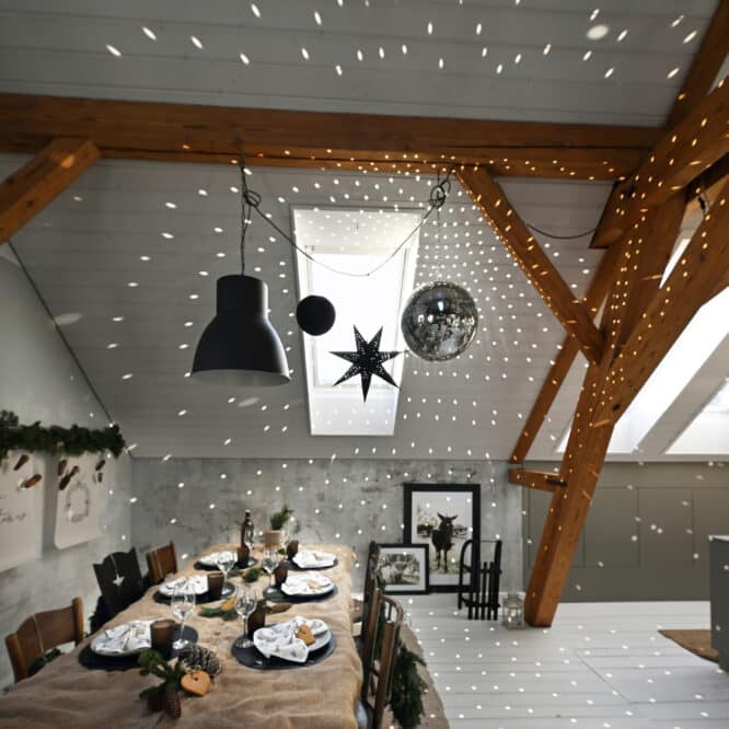 Salle à manger mansardée avec plafond en pente, poutres apparentes et décorations festives.