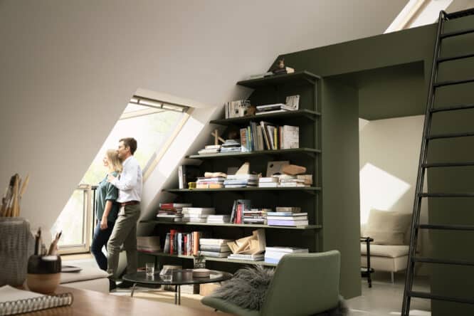 Chambre mansardée avec plafond en pente, fenêtre de toit VELUX et bibliothèque.