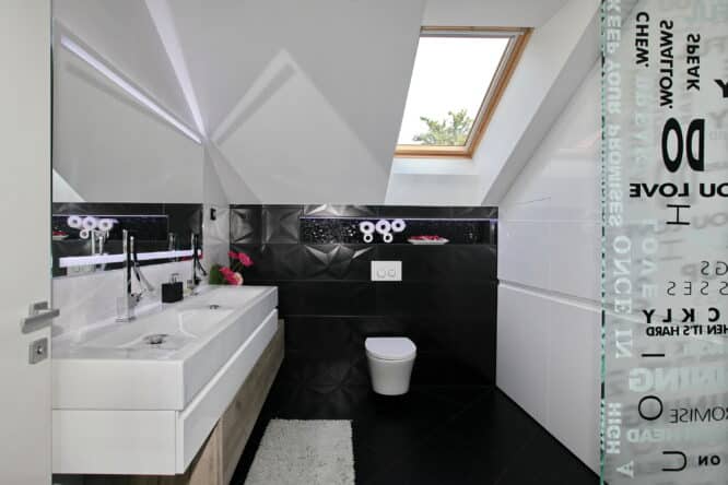 Salle de bains dans les combles avec des sous-pentes et un sol en noir.