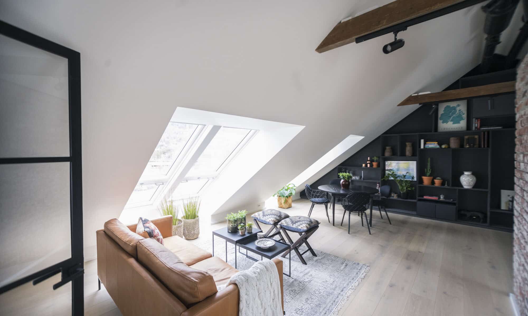 Espace de vie mansardé avec plafond incliné, fenêtres de toit VELUX et décoration moderne.