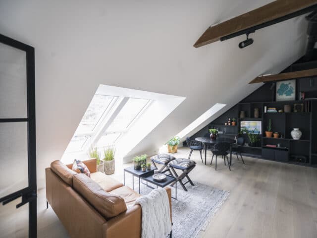 Espace de vie mansardé avec plafond incliné, fenêtres de toit VELUX et décoration moderne.