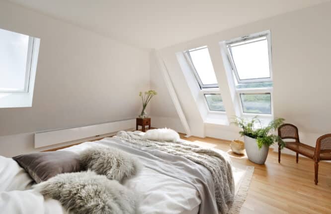 Chambre mansardée avec plafond en pente et fenêtres de toit VELUX, confortable et lumineuse.