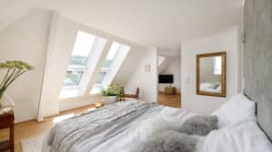 Chambre mansardée avec plafond en pente et fenêtres de toit VELUX, laissant entrer la lumière naturelle.