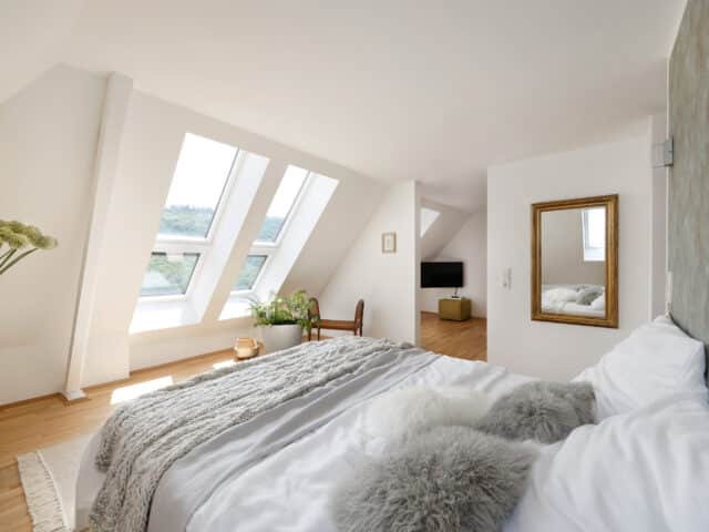 Chambre mansardée avec plafond en pente et fenêtres de toit VELUX, laissant entrer la lumière naturelle.