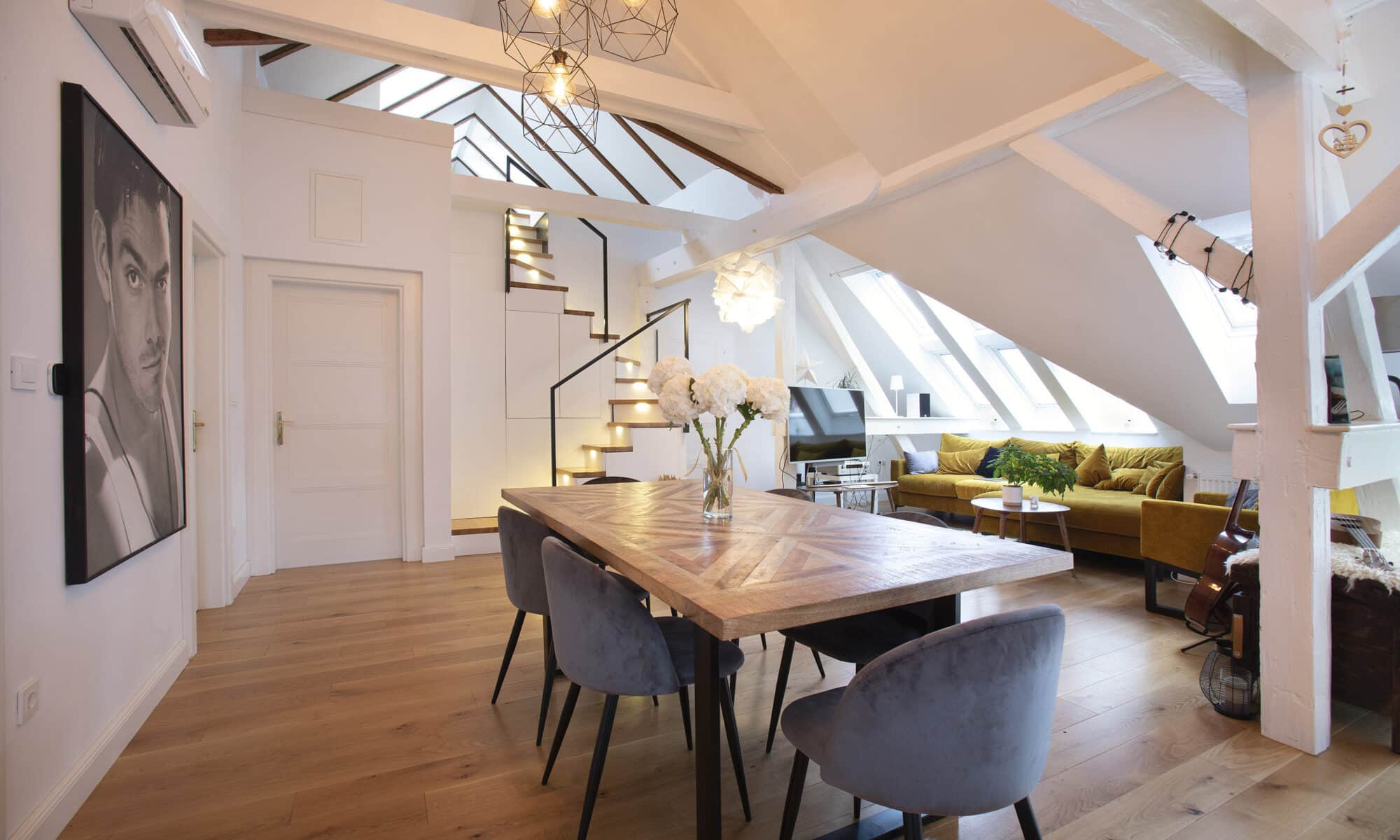 Espace de vie mansardé avec plafond incliné, fenêtres de toit VELUX et mobilier moderne.