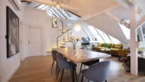 Espace de vie mansardé avec plafond incliné, fenêtres de toit VELUX et mobilier moderne.