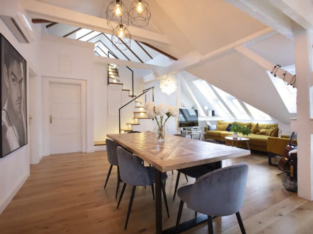 Espace de vie mansardé avec plafond incliné, fenêtres de toit VELUX et mobilier moderne.