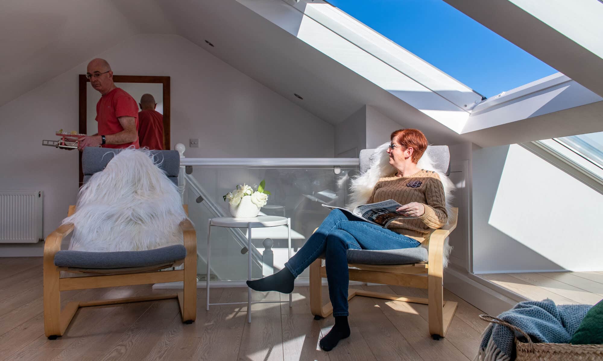Chambre mansardée avec plafond incliné et fenêtre de toit VELUX, coin salon confortable.