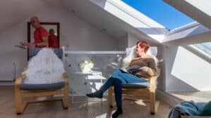 Chambre mansardée avec plafond incliné et fenêtre de toit VELUX, coin salon confortable.
