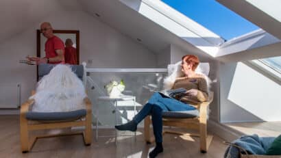 Chambre mansardée avec plafond incliné et fenêtre de toit VELUX, coin salon confortable.