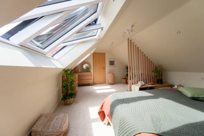 Chambre mansardée avec de grandes fenêtres de toit et des couleurs douces de linge de lit (vert sauge et terracotta)