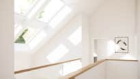 Palier mansardé avec plafond incliné et plusieurs fenêtres de toit VELUX laissant entrer la lumière naturelle.