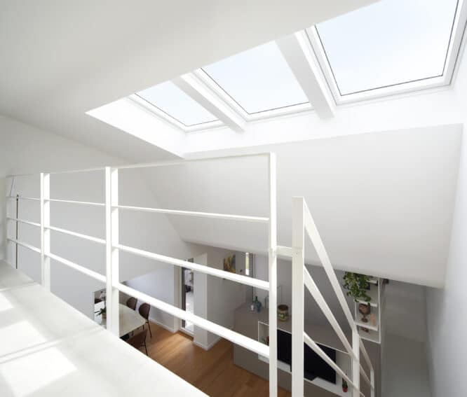 Grenier avec plafond en pente et fenêtres de toit VELUX, intérieur lumineux et moderne.