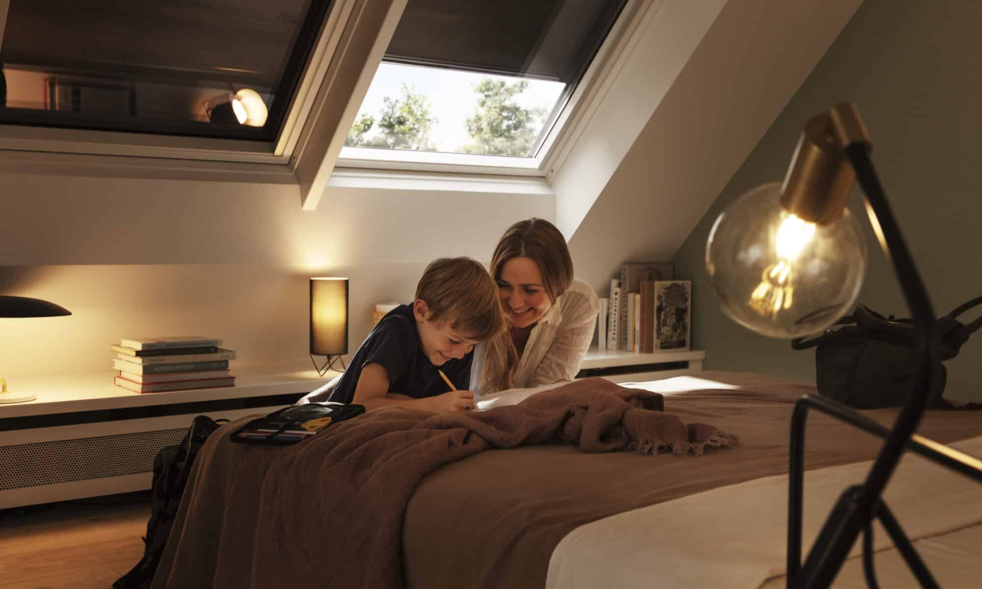 Chambre mansardée avec plafond incliné et fenêtre de toit VELUX, confortable et accueillante.