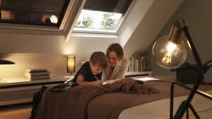 Chambre mansardée avec plafond incliné et fenêtre de toit VELUX, confortable et accueillante.