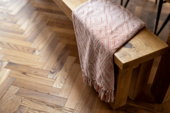 Banc en bois avec une couverture à motifs sur un plancher en bois.