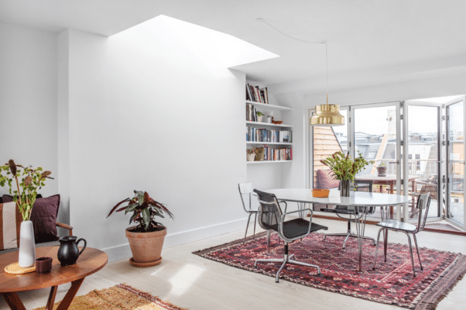 Salle à manger avec fenêtre de toit VELUX, table ronde et accès au balcon.