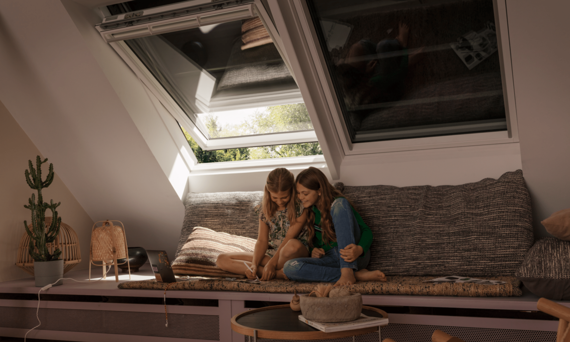 Pièce mansardée avec plafond en pente et fenêtre de toit VELUX ouverte, coin salon confortable.