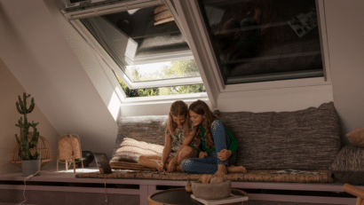 Pièce mansardée avec plafond en pente et fenêtre de toit VELUX ouverte, coin salon confortable.