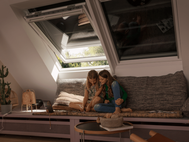 Pièce mansardée avec plafond en pente et fenêtre de toit VELUX ouverte, coin salon confortable.