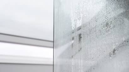 Gros plan sur des gouttelettes de condensation sur une surface en verre, créant un motif texturé.