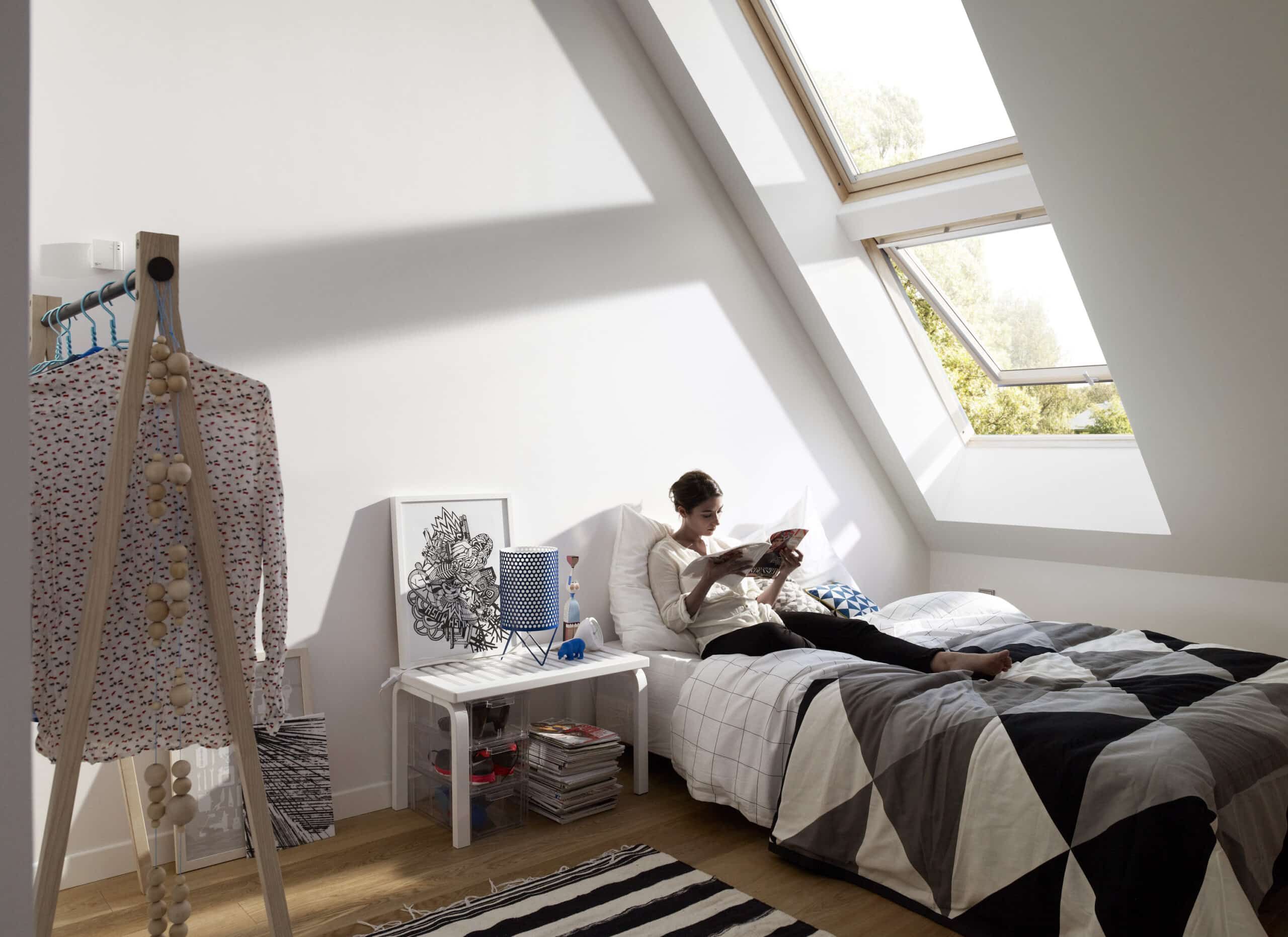 Chambre mansard&eacute;e avec plafond en pente et fen&ecirc;tre de toit VELUX, laissant entrer abondamment la lumi&egrave;re naturelle.