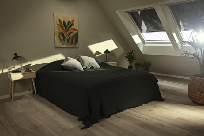 Chambre mansard&eacute;e avec plafond en pente et fen&ecirc;tre de toit VELUX, laissant entrer la lumi&egrave;re naturelle.