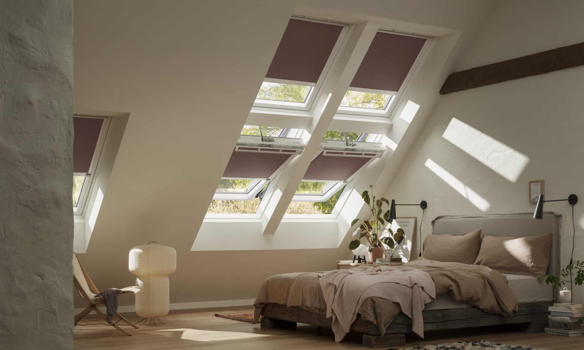 Chambre mansardée avec plafond en pente et fenêtres de toit VELUX, confortable et lumineuse.