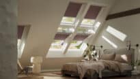 Chambre mansardée avec plafond en pente et fenêtres de toit VELUX, confortable et lumineuse.